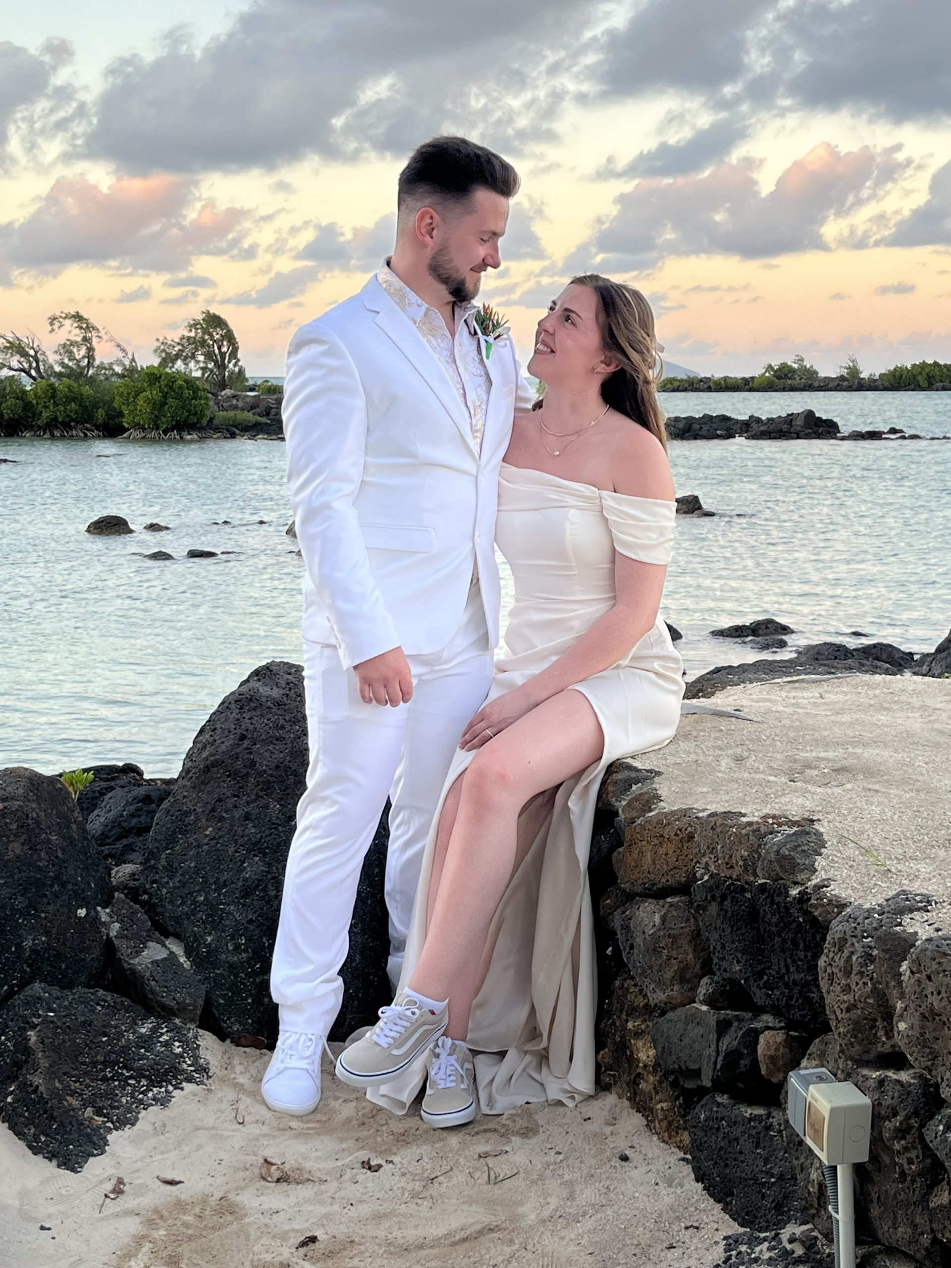 A picture a married couple dressed in white in front of a beautiful sunset in Mauritius