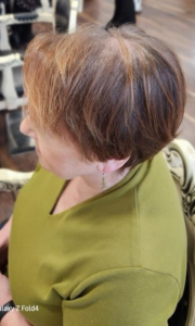 A woman at the hair dresser showing signs of female hair loss on the top of her head
